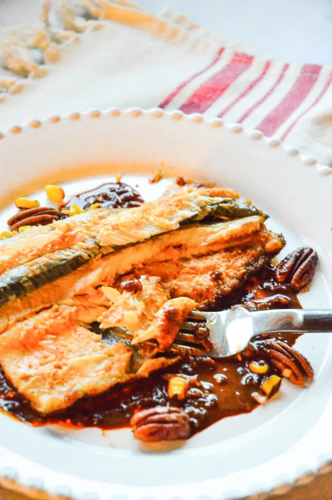 Rainbow trout recipe with red chili sauce on white plate