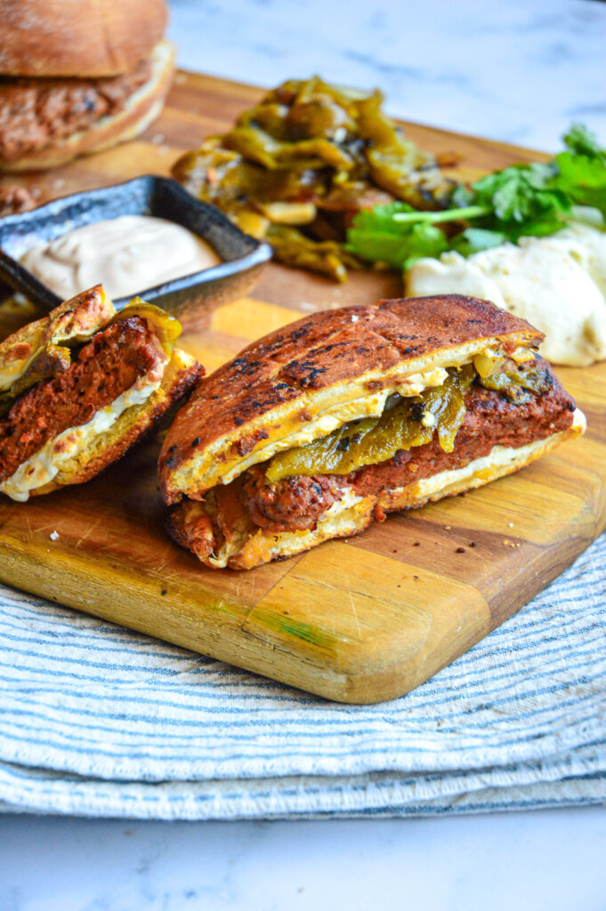 chorizo burger on cutting board with green chiles and cheese