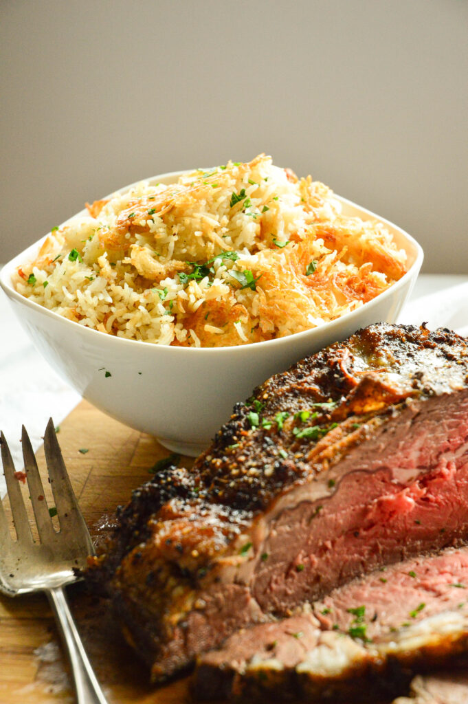 baked rice side dishes with roast beef on cutting board