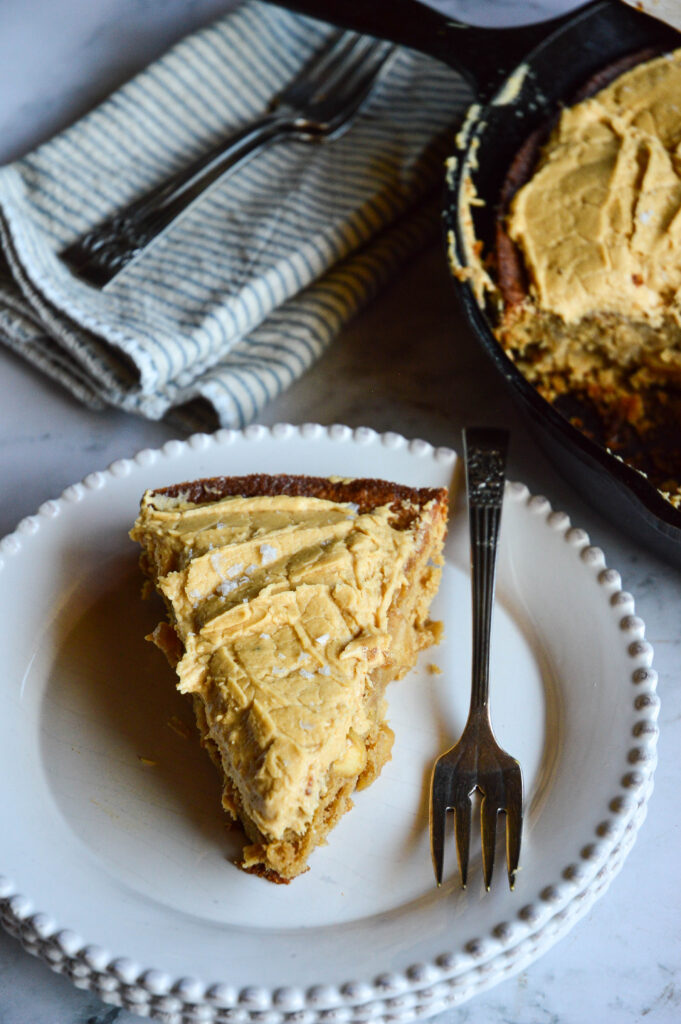 slice of skillet apple cake with salted caramel frosting on white plate with fork