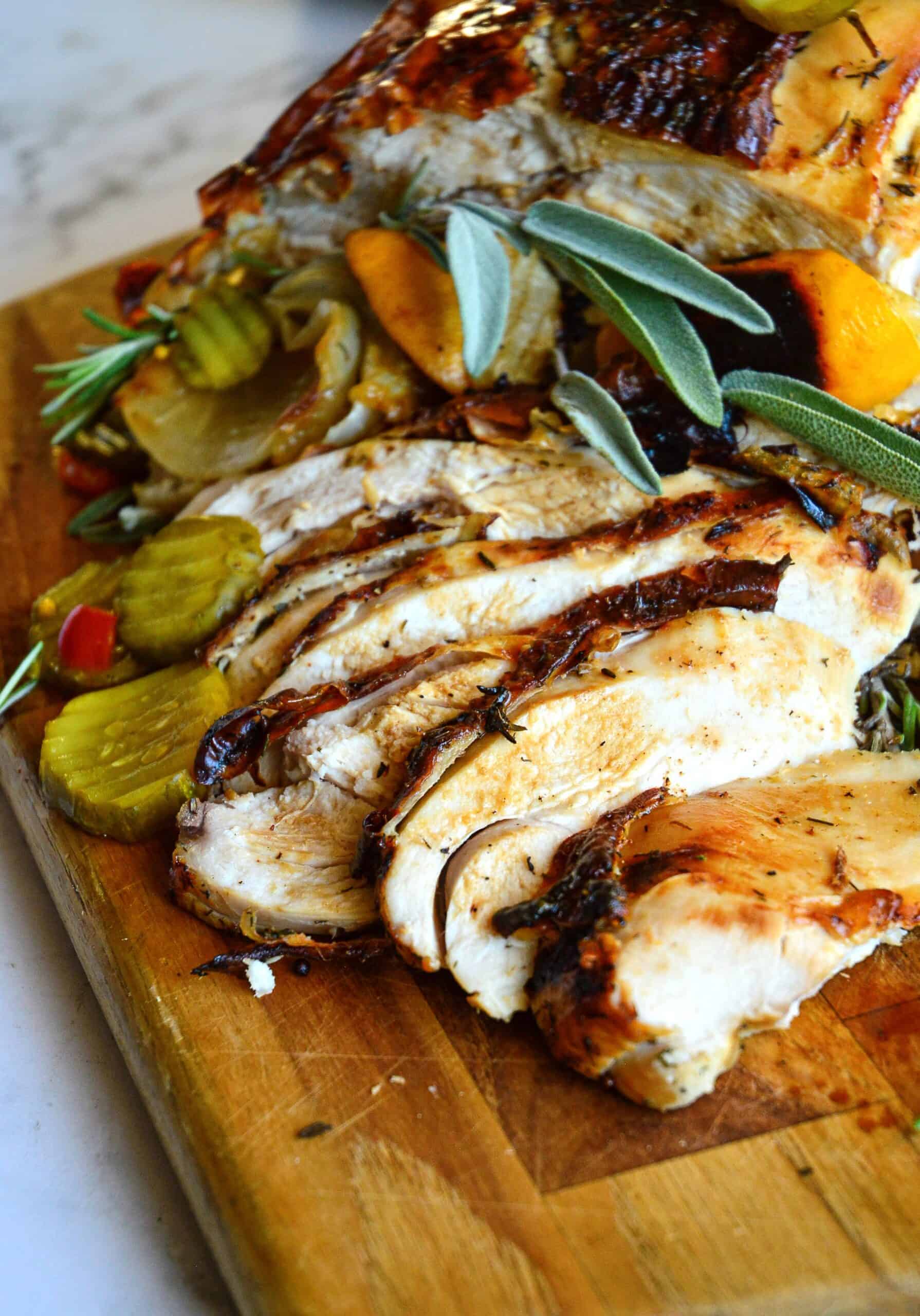 sliced turkey breast on cutting board with pickles