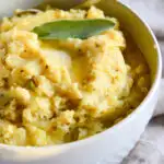 Thanksgiving mashed potatoes and gravy recipe in white bowl with silver spoon
