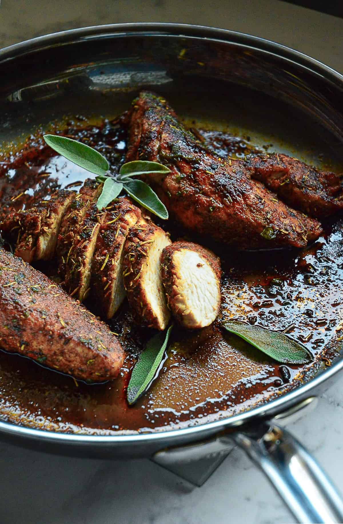 turkey breast tenderloins in skillet with one sliced