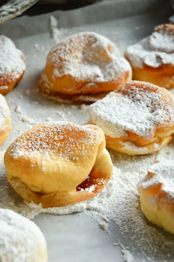 Hanukkah jelly donuts recipe with powdered sugar on parchment tray