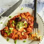 Chipotle Red Sauce Recipe over chicken breast on white plate with knife and fork