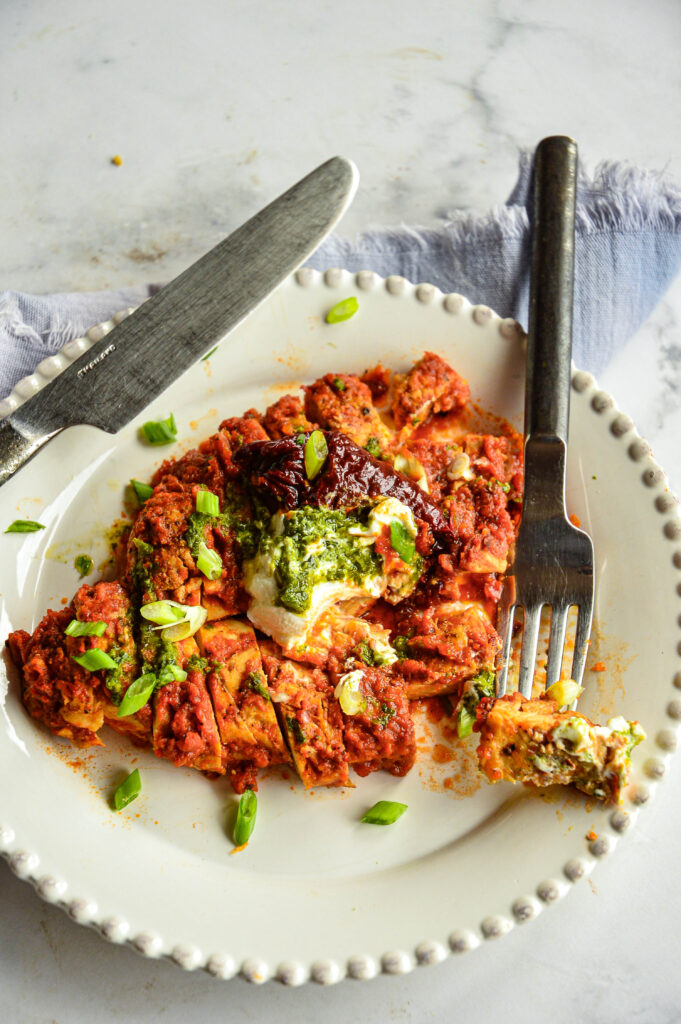 Chipotle Red Sauce Recipe over chicken breast on white plate with knife and fork