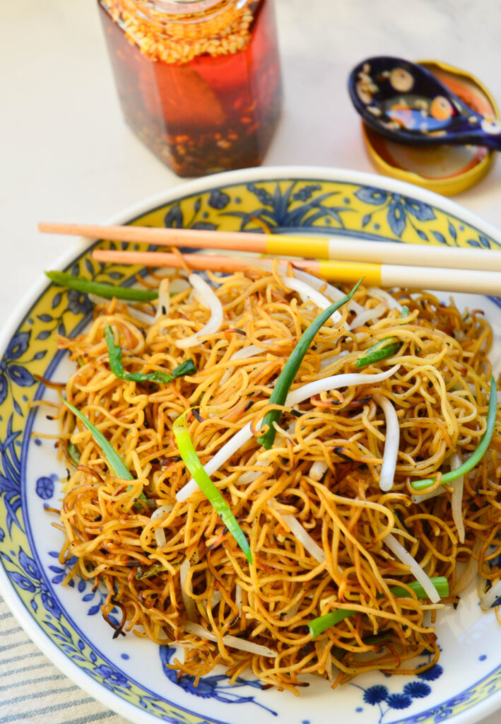 chow mein recipe in asian bowl with chopsticks and chili oil