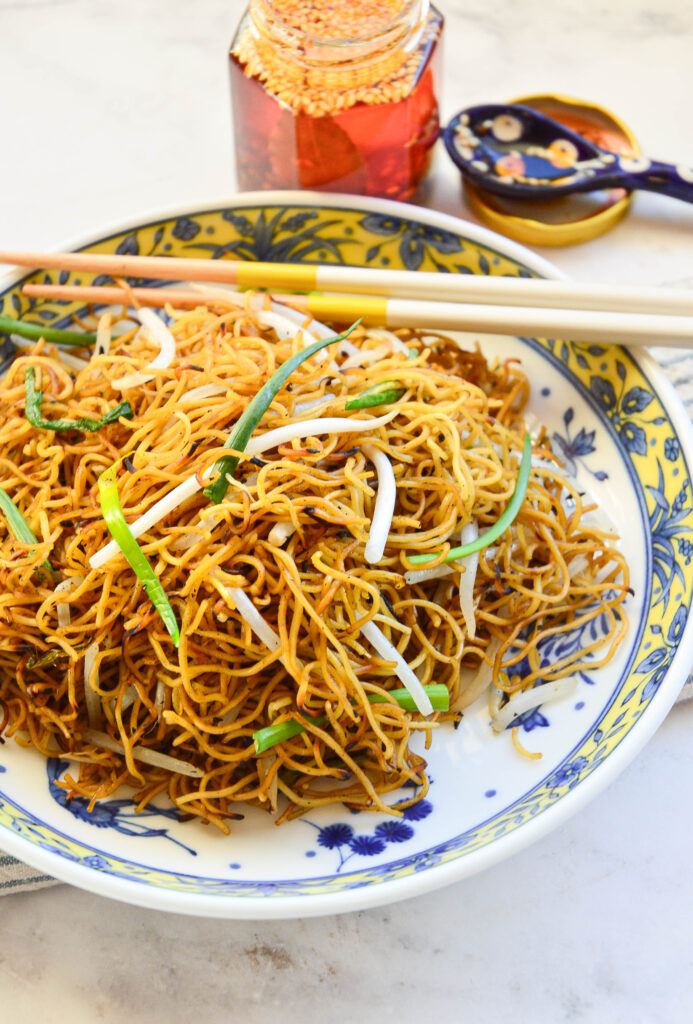 bowl of chow mein noodles with chopsticks and chili oil