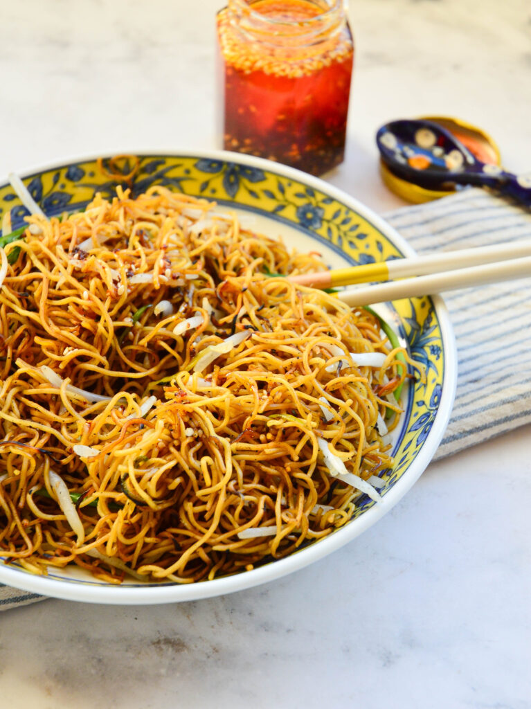 chow mein recipe in asian bowl with chop sticks and chile oil