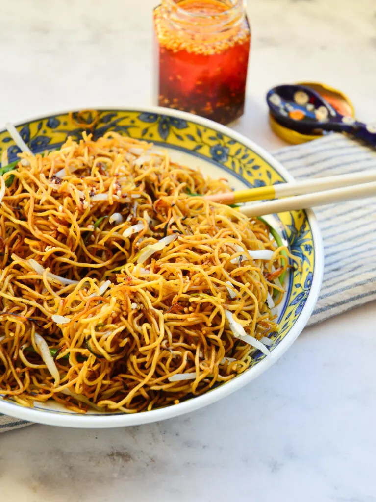 chow mein recipe in asian bowl with chop sticks and chile oil