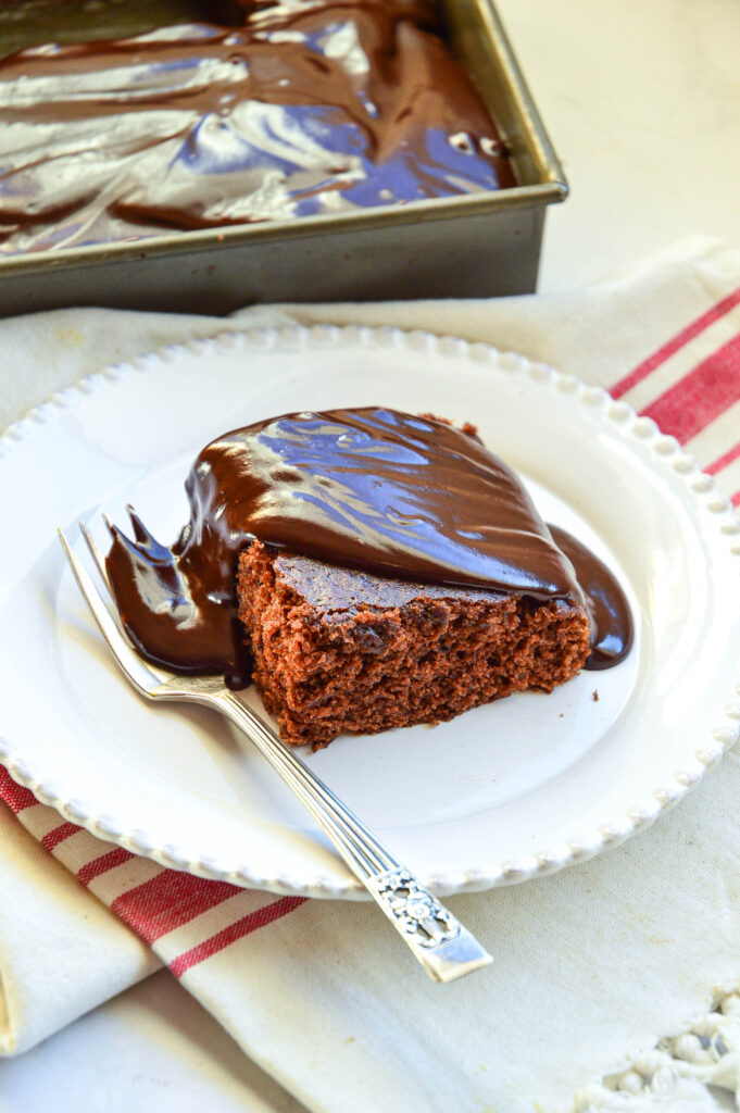 no diary chocolate cake recipe with glaze on white plate with fork