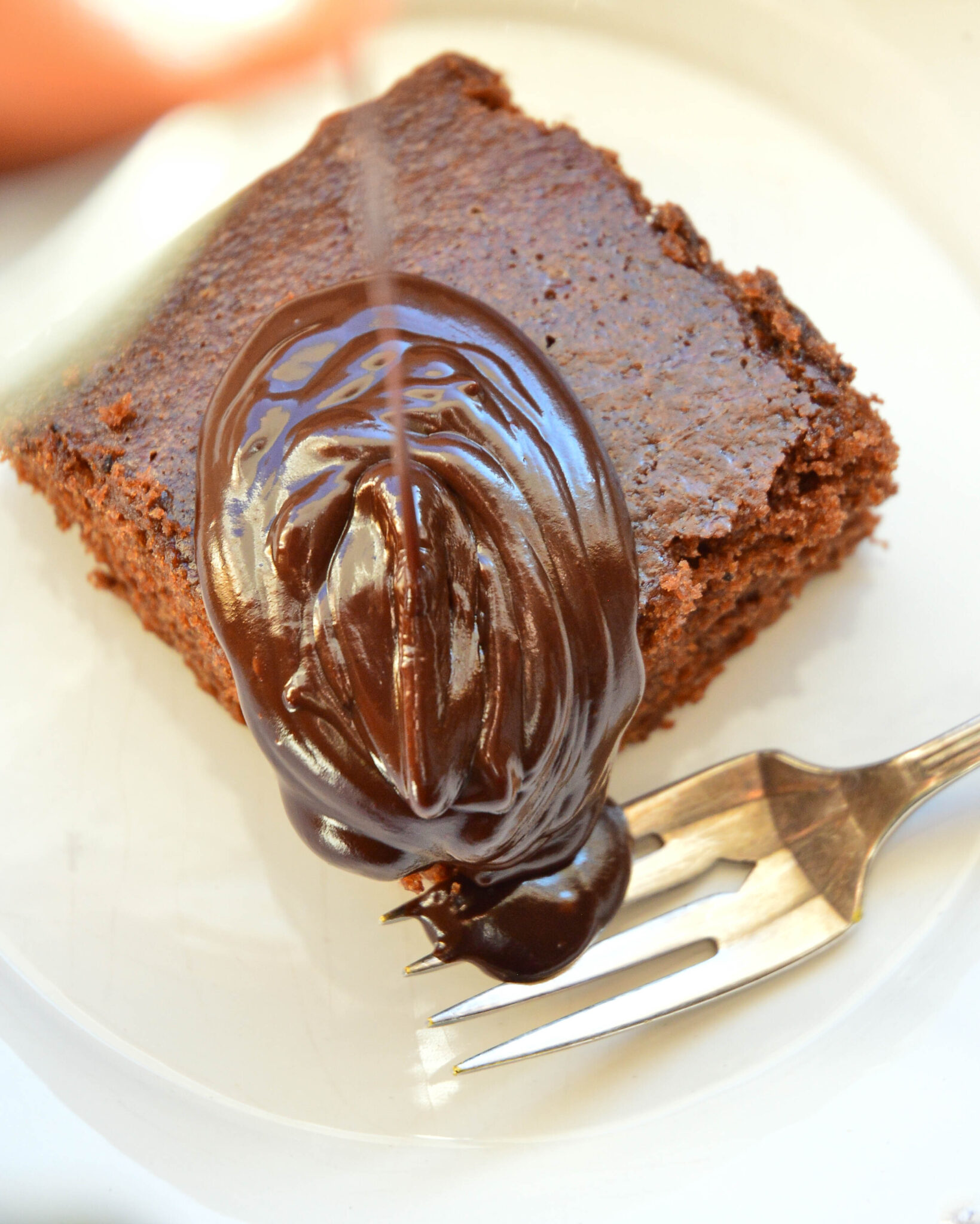 no dairy chocolate cake recipe on white plate with glaze being poured on
