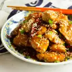 Chinese Sweet and Spicy Chicken (Sesame Chicken in Asian bowl with orange chopsticks