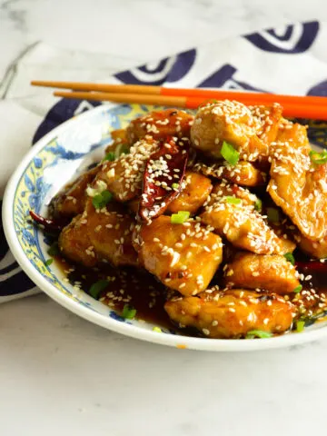 Chinese Sweet and Spicy Chicken (Sesame Chicken in Asian bowl with orange chopsticks