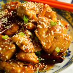 Sesame Chicken in Asian bowl with orange chopsticks (Chinese Sweet and SPicy Chicken Recipe)