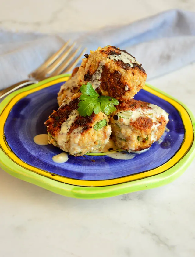 spiced ground chicken meatballs on blue plate with tahini