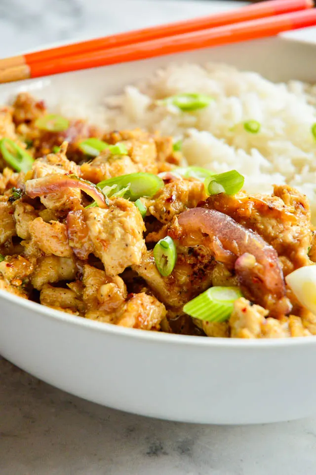 lemongrass chicken Vietnamese recipe in white bowl with orange chopsticks.