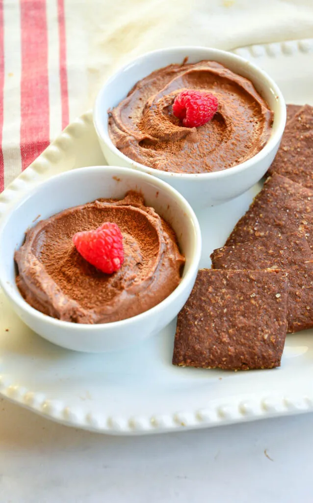 2 white dessert dishes with nutella mousse and cookies.