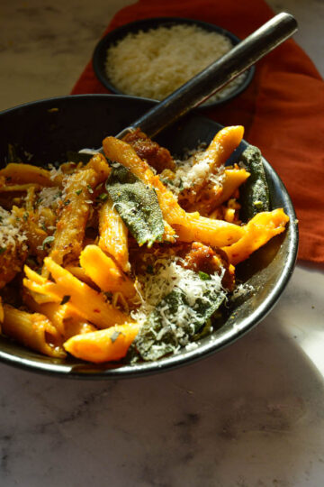 black bowl with pumpkn pasta sauce with sausage