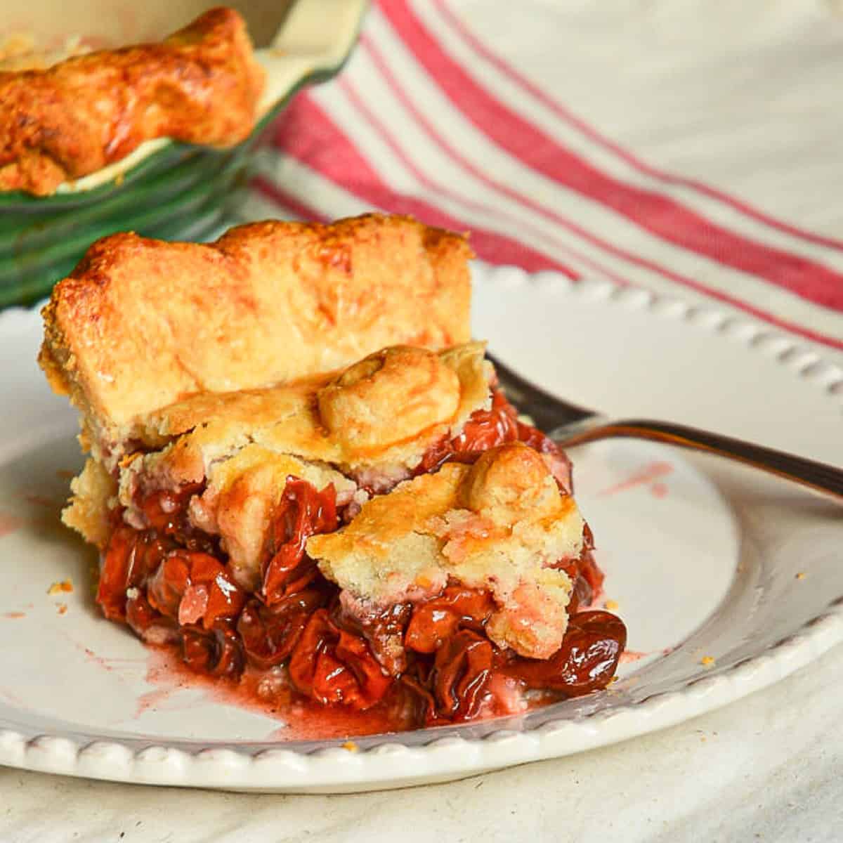 slice of cherry pie on white plate with fork