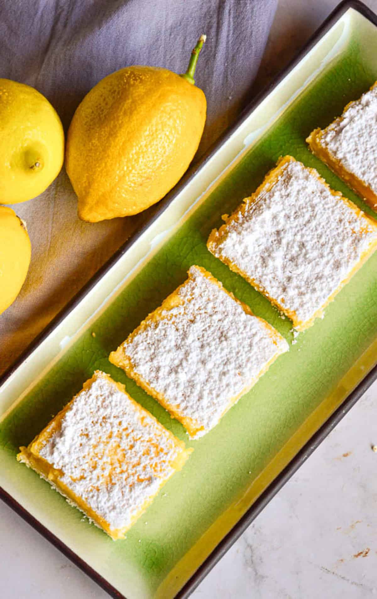 Lemon Bars on Green plate dusted with powdered sugar