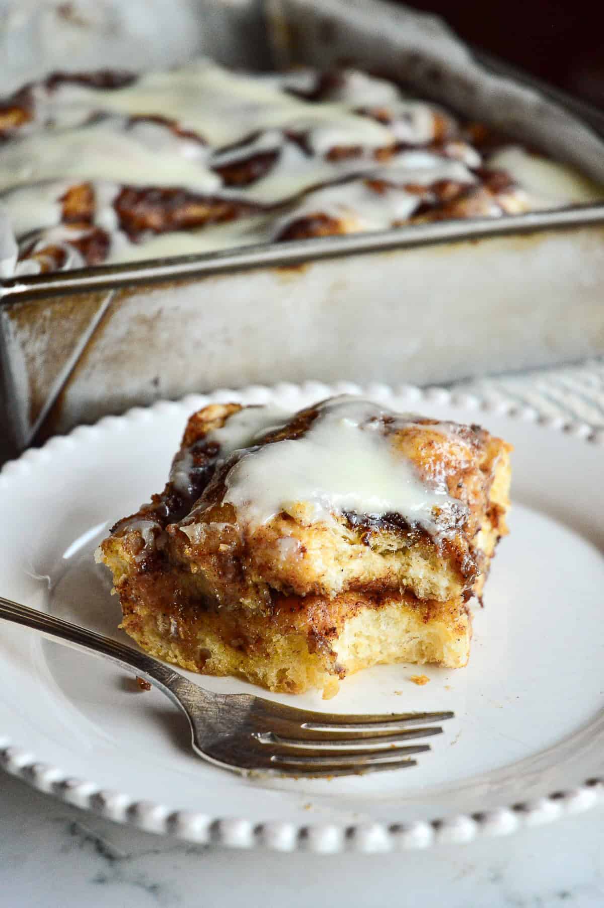 cinnamon roll focaccia with bite taken out on white plate with fork close up