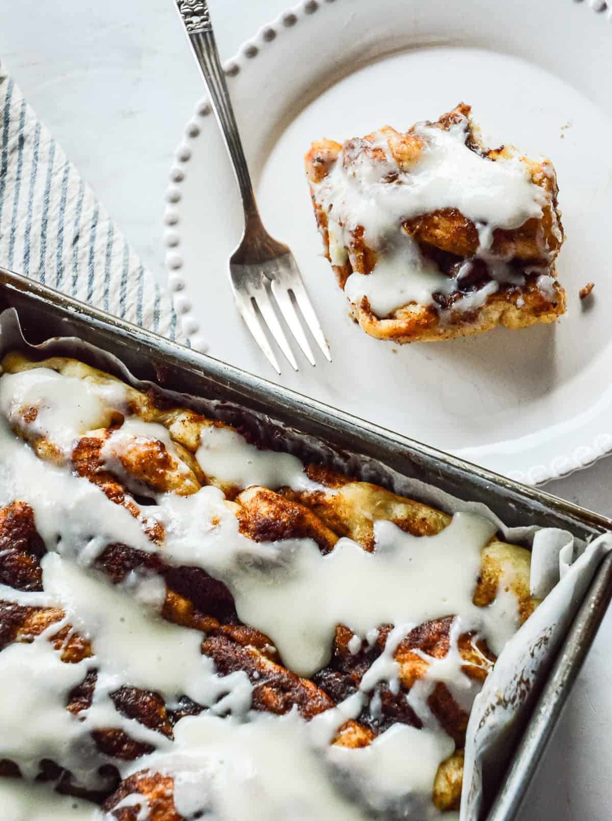 cinnamon roll focaccia in pan and a square on white plate with fork