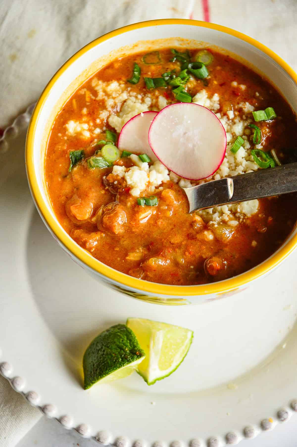 refied bean soup with spoon in yellow rimmed bowl with garnishes