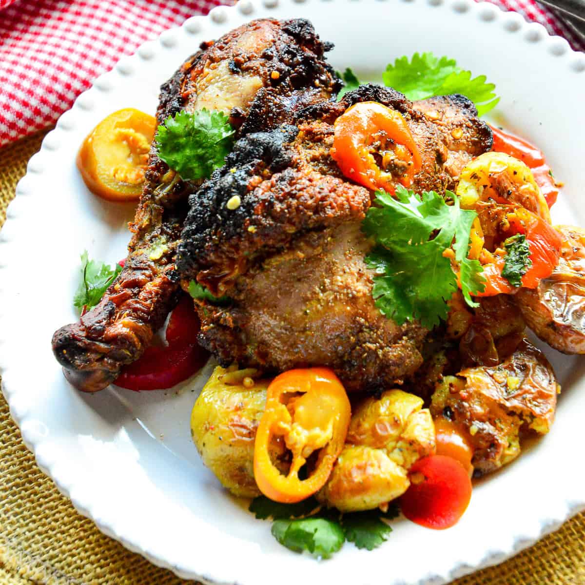 grilled jerk chicken on white plate with banana peppers
