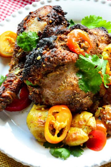 grilled banana pepper chicken on white plate with red check na[kin