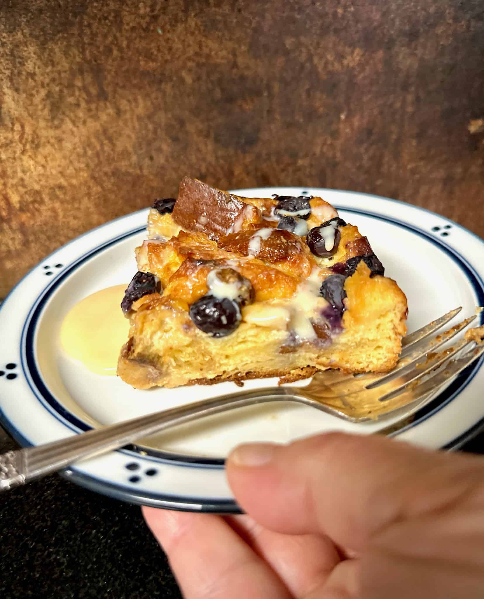 square of baked french toast casseroleon blue rimmed plate with fork