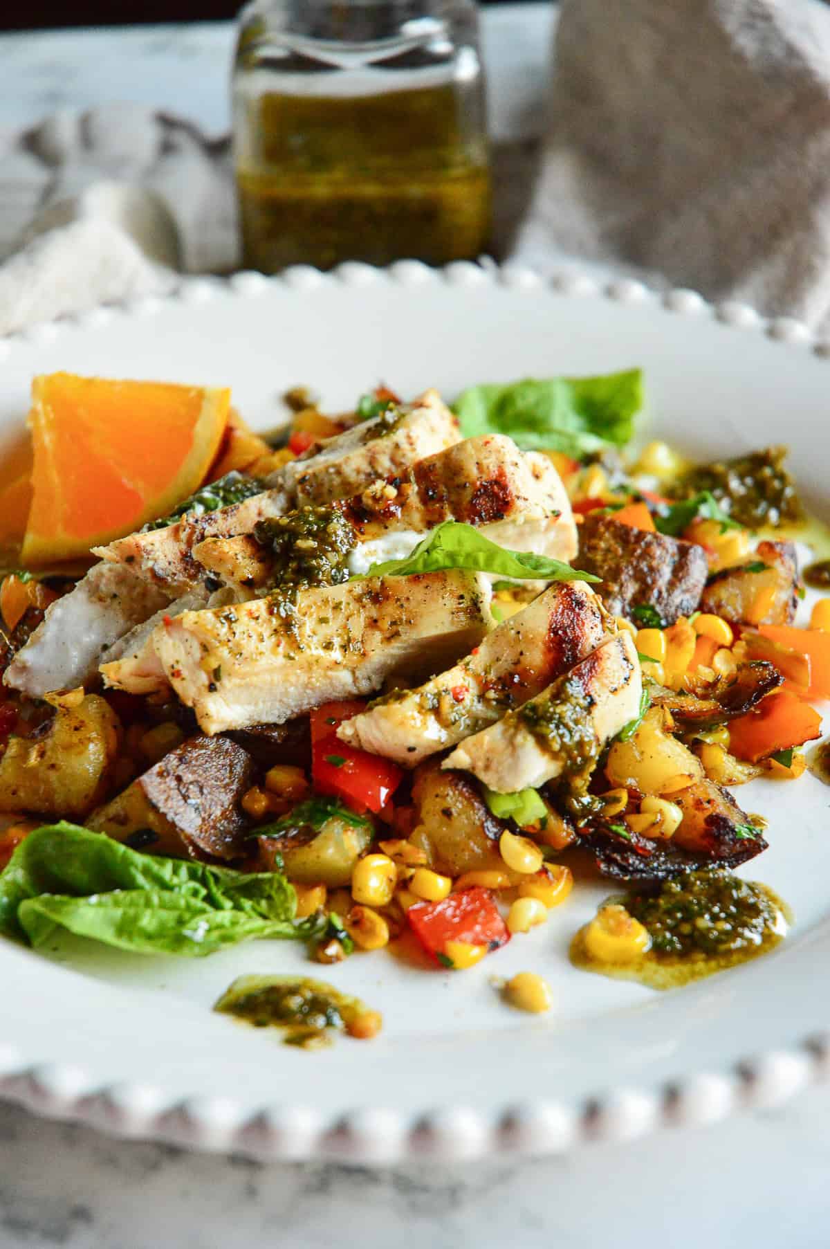 grilled goat cheese chicken with jar of basil vinaigrette in background