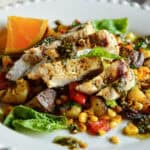 chicken with goat cheese on bed of veggies on white plate