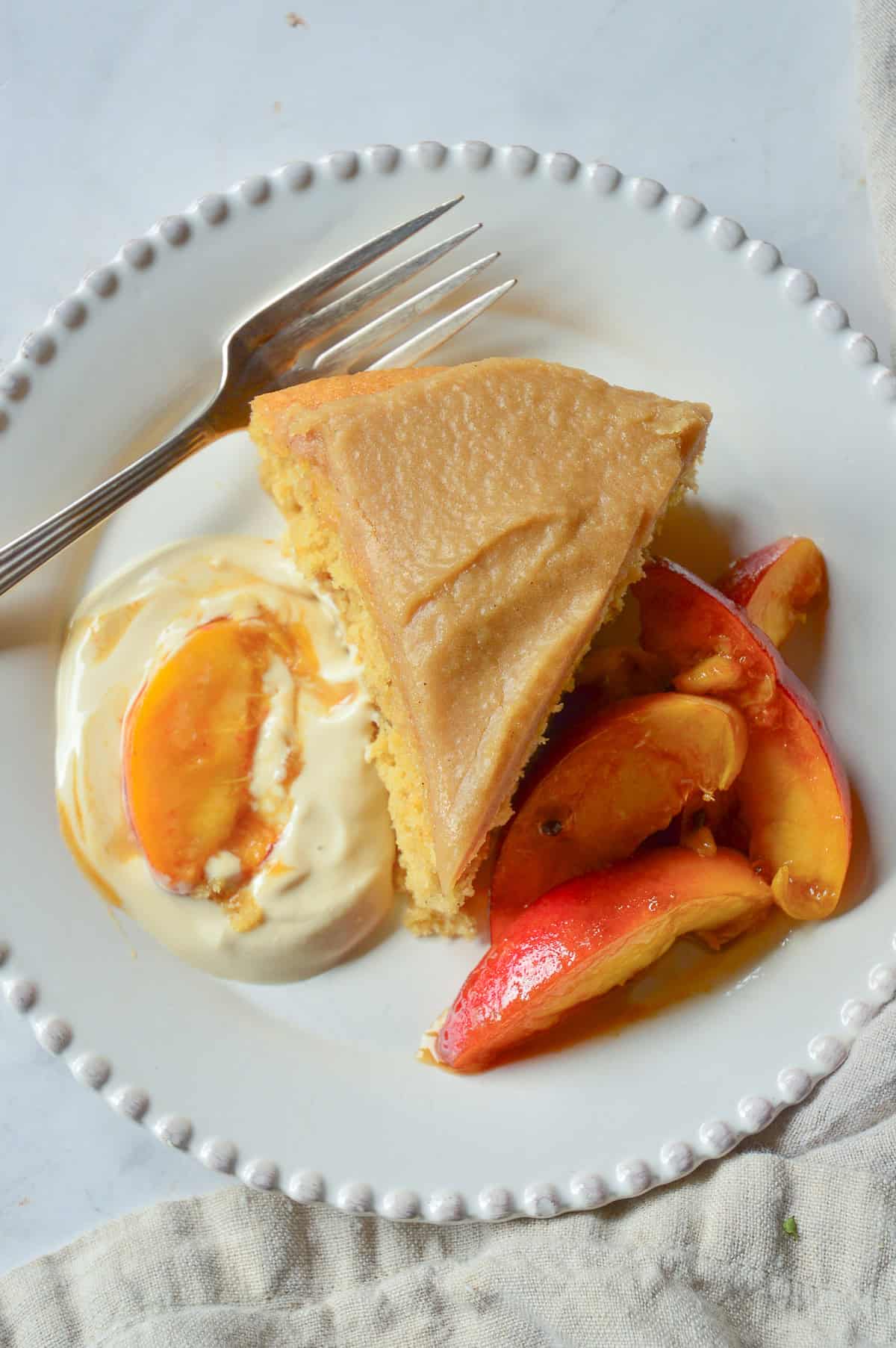 butteermilk cake recipe slic of cake on white plate with fresh peaches and brown sugar sour cream