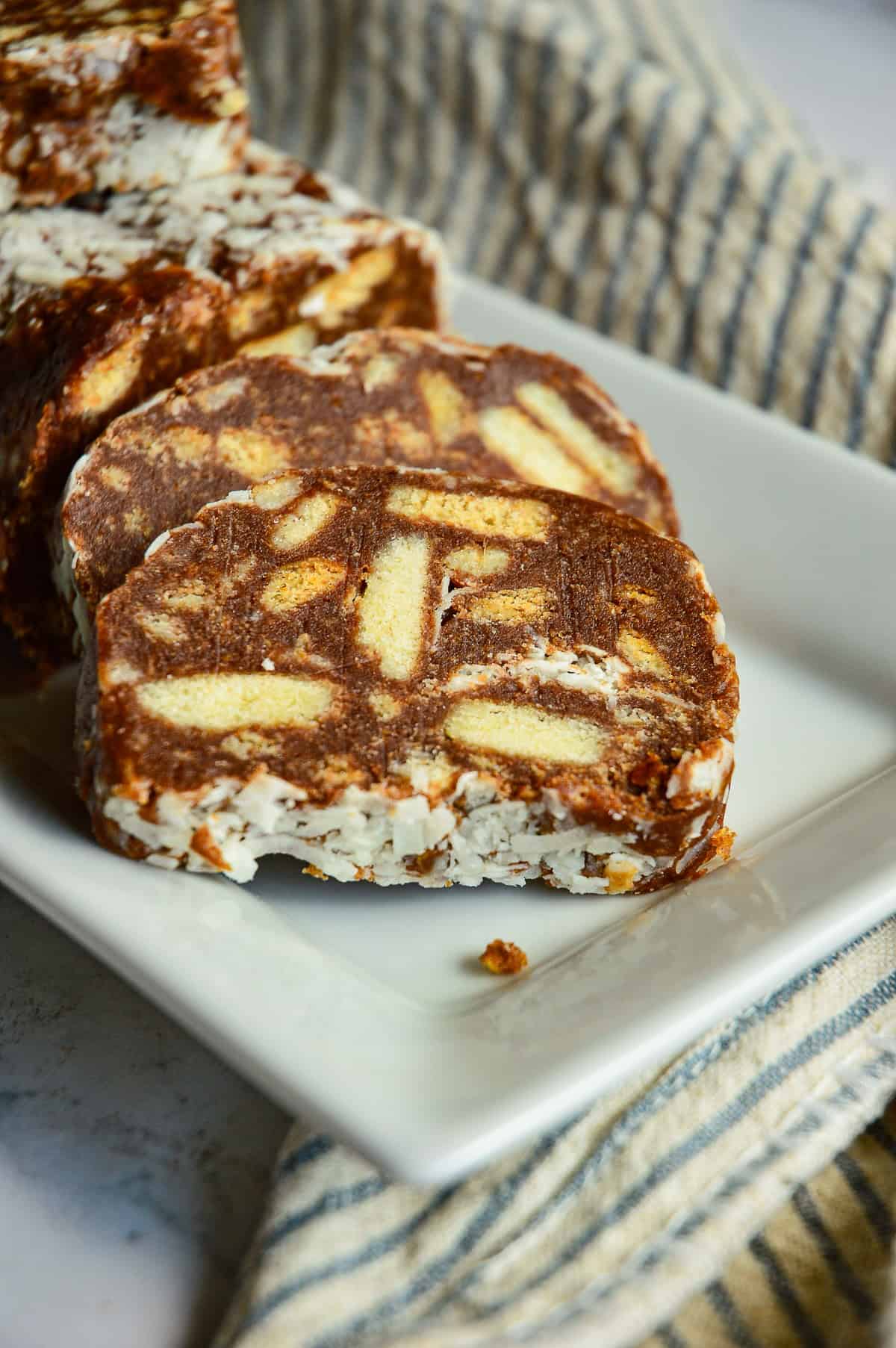 slices of chocolate salami recipe on whitee rectangle plate with blue stripe napkin