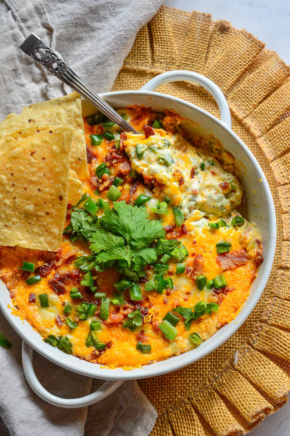jalapeno popper dip recipe in white baking dish with serving spoon and tortilla chips