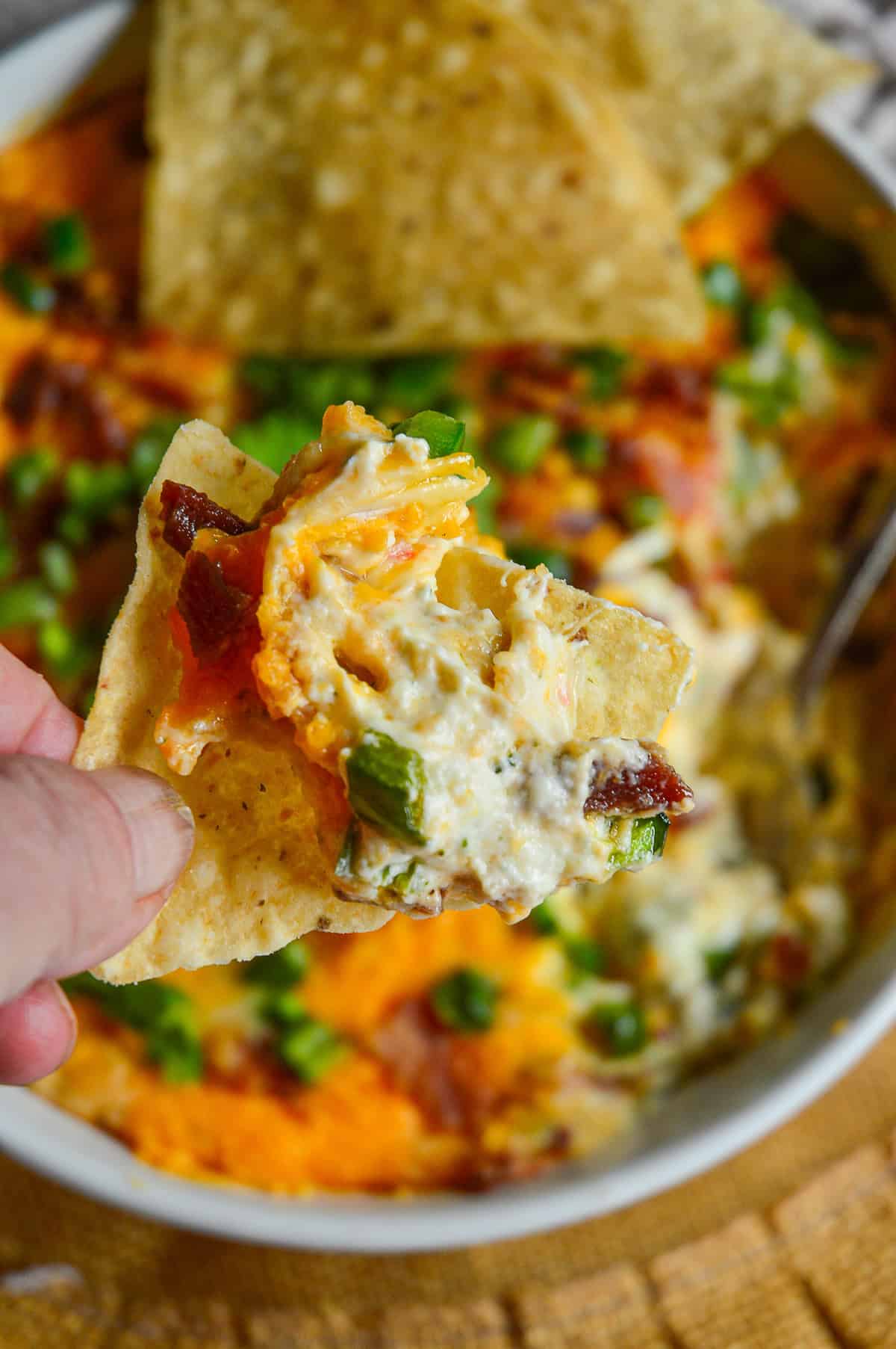 tortillaa chip topped with jalapeno popper dip over bowl