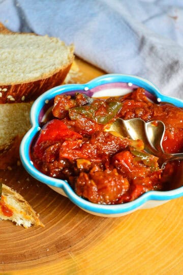 tomato matbucha recipe in decorative blue rimmed bowl with silver spoon