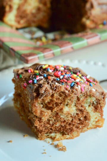 marble cake square on white plate with marble cake in background