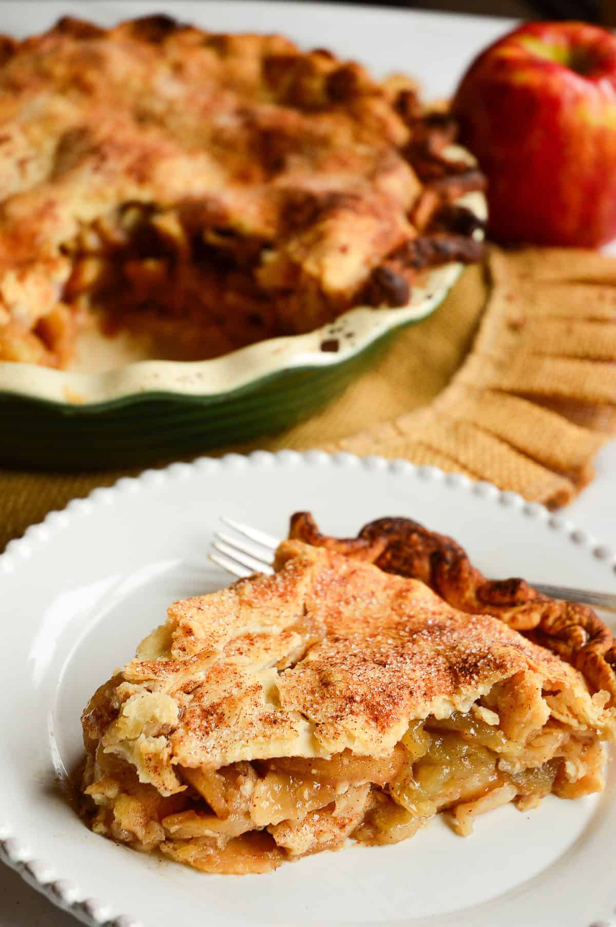 slice of apple pie with pie in background