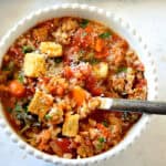 farro soup in white bowl with rustic spoon