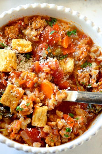 farro soup in white bowl with rustic spoon