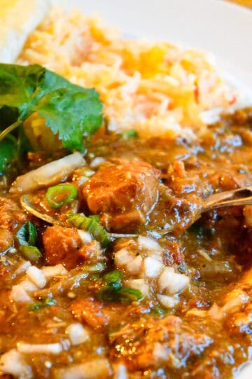colorado pork green chili on plate with spoon and rice in background