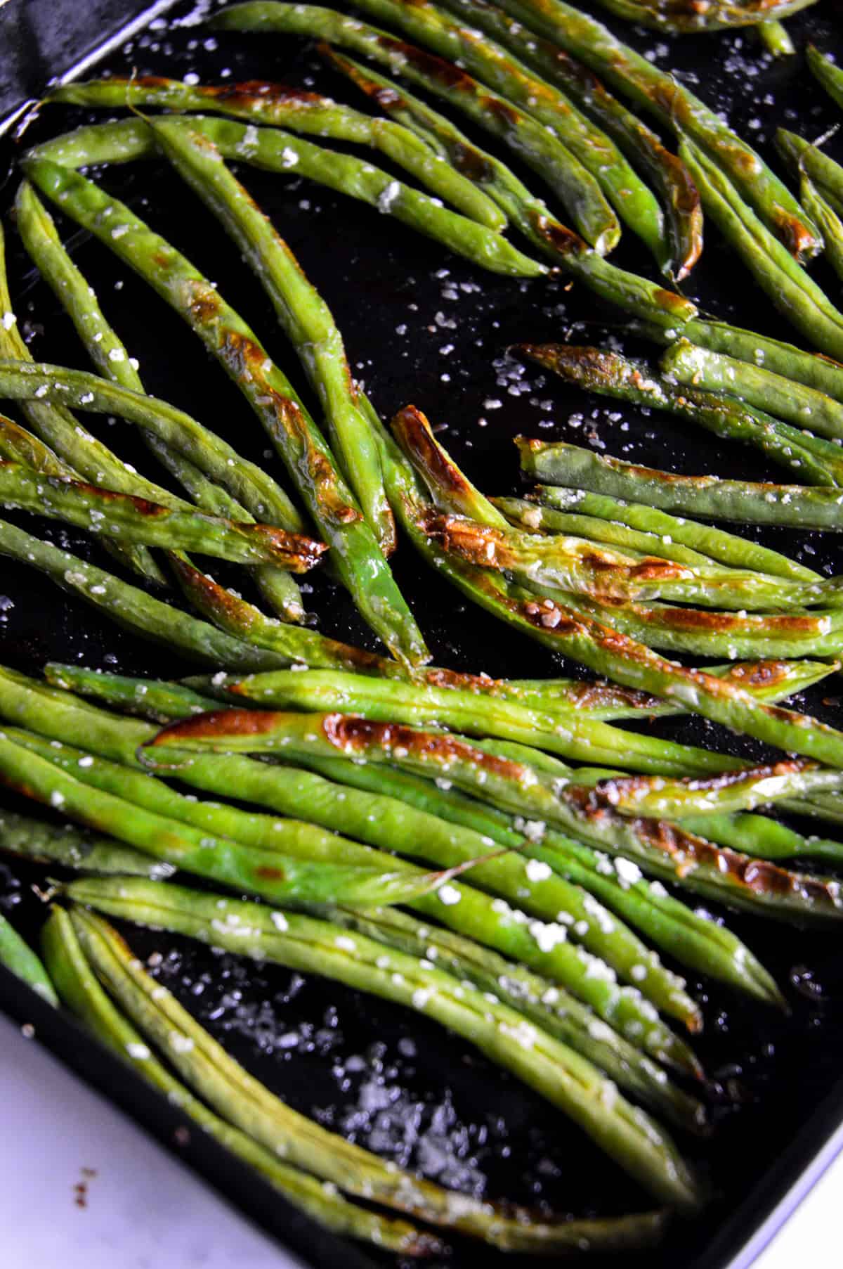 roasted green beans on black pan