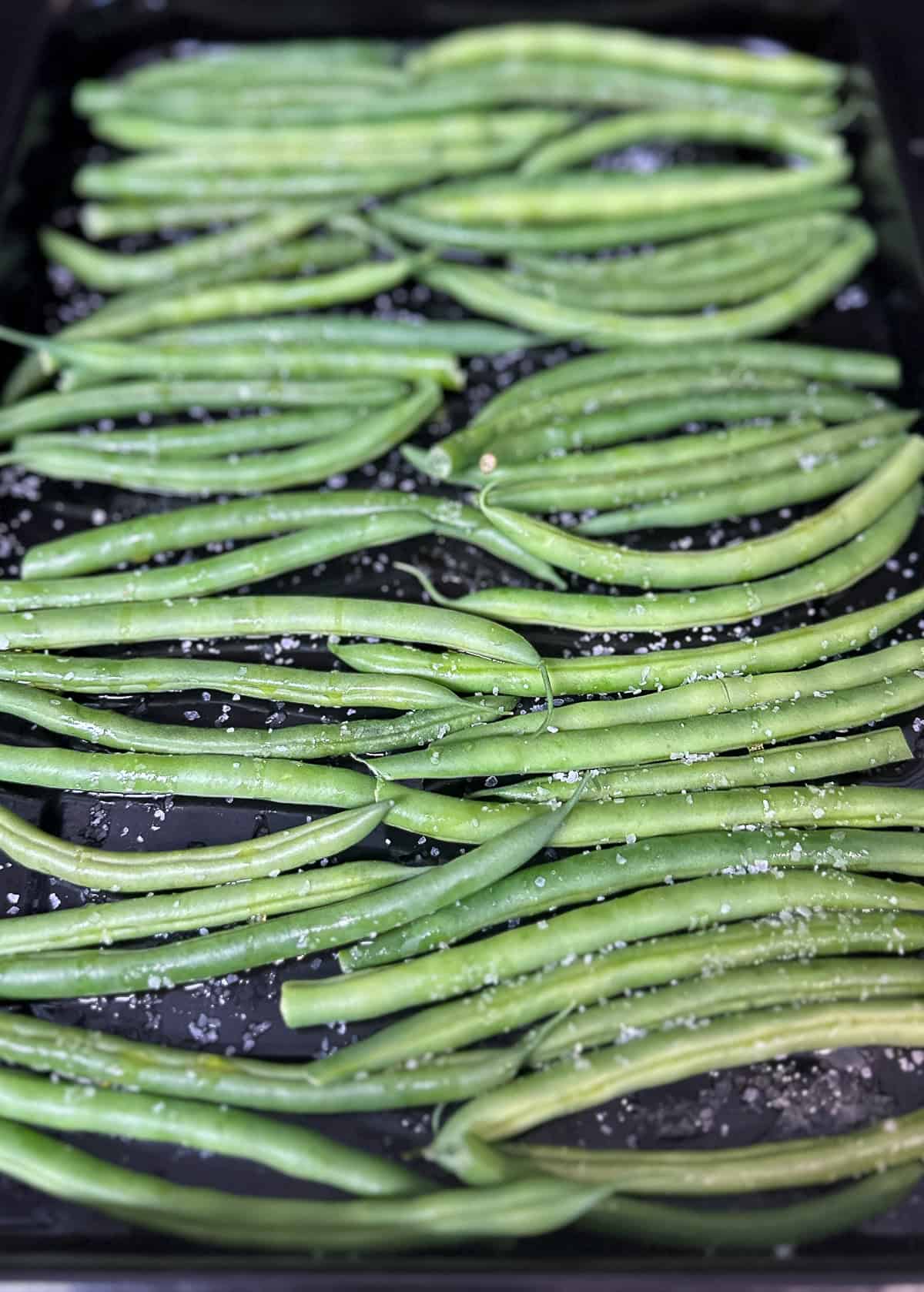 raw green beans on baking sheet with salt