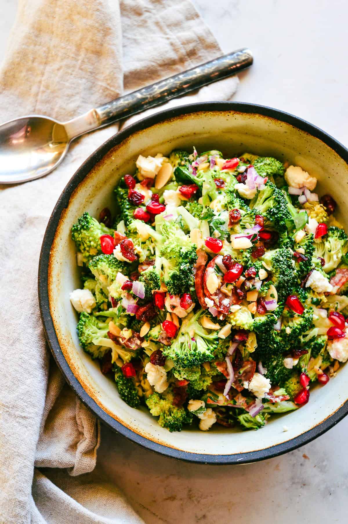 broccoli cranberry salad in earthen bowl with napkin and serving spoon