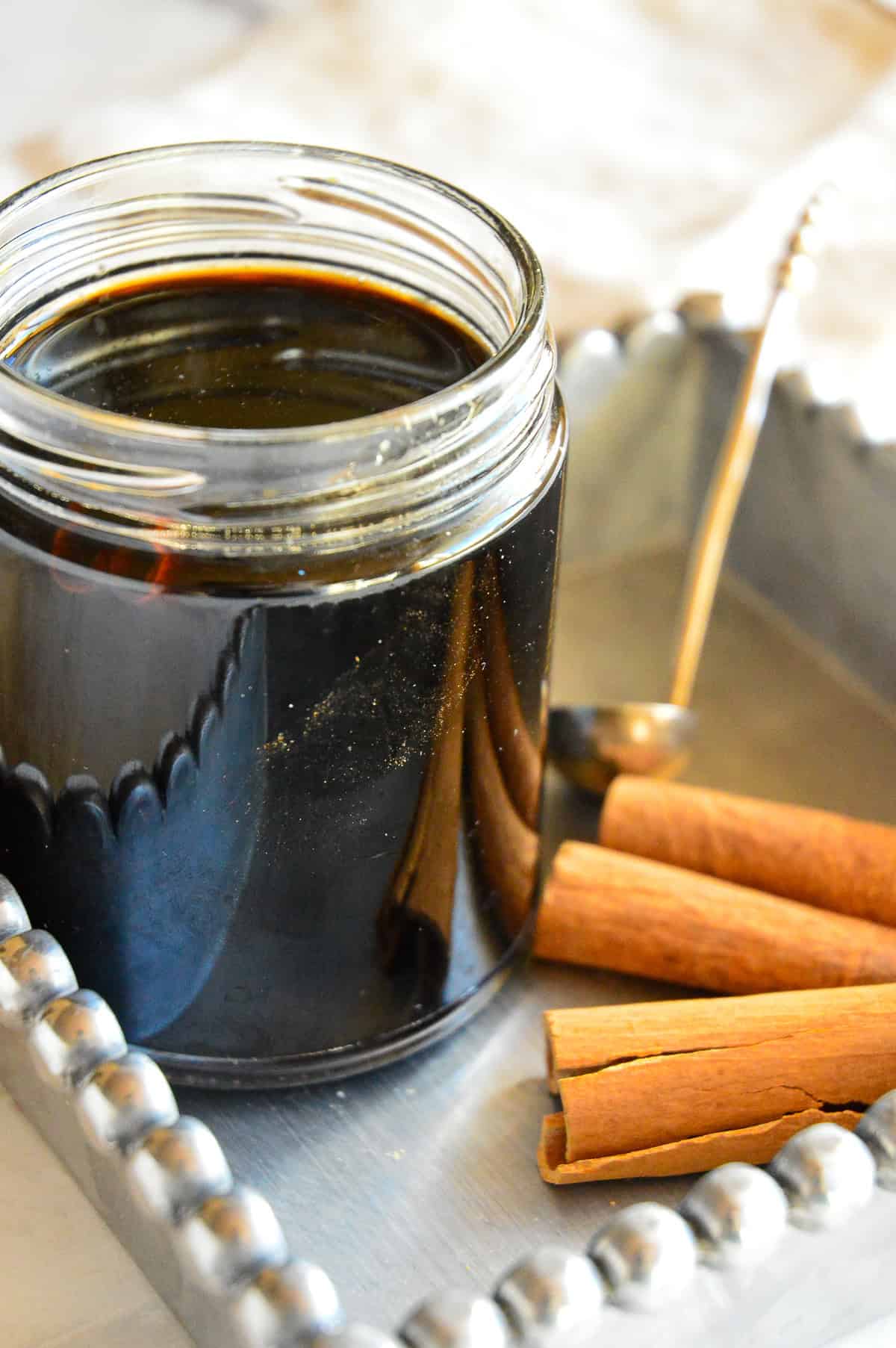 cinnamon syrup in jar with cinnamon sticks on tray