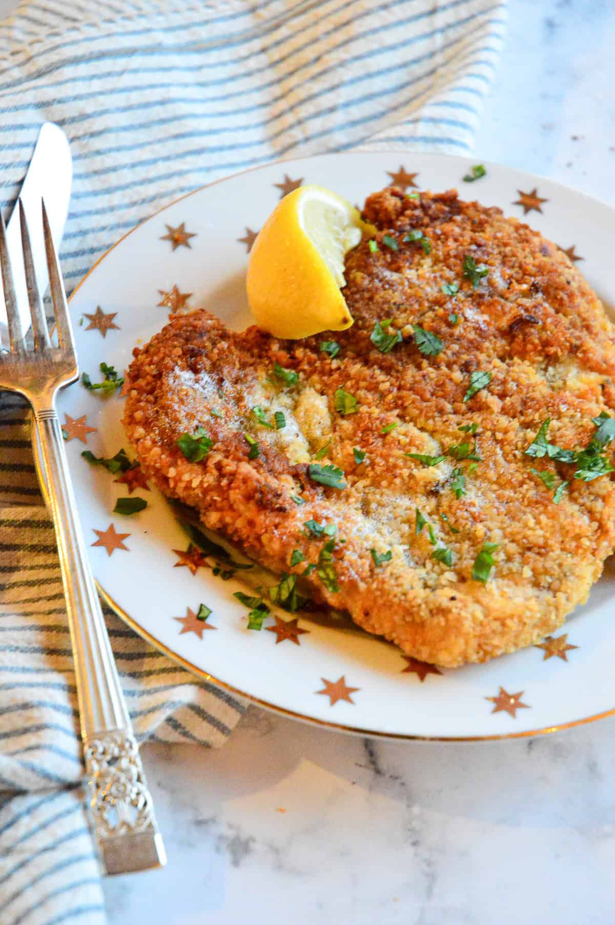 chicken  schnitzel with lemon on white star plate with blue stirpe napkin