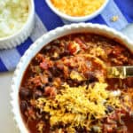 black bean chili recipe topped with cheese and onions in white bowl