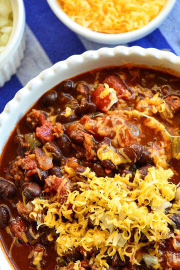 black bean chili recipe topped with cheese and onions in white bowl